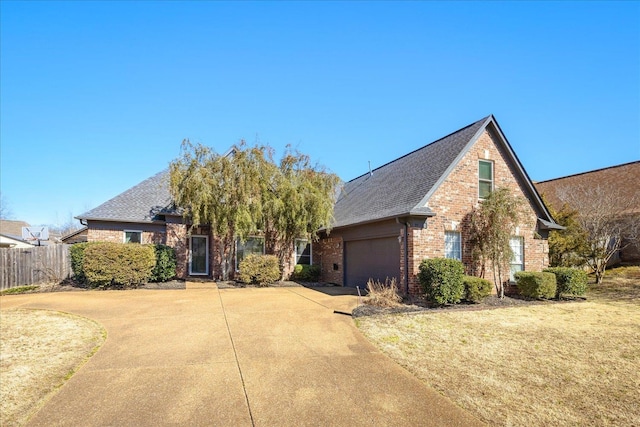 view of front of house featuring concrete driveway, roof with shingles, fence, a front lawn, and brick siding