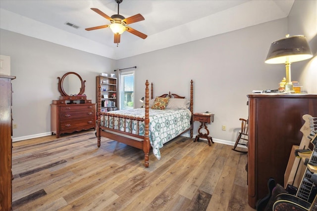 bedroom with light wood-style floors, baseboards, visible vents, and a ceiling fan