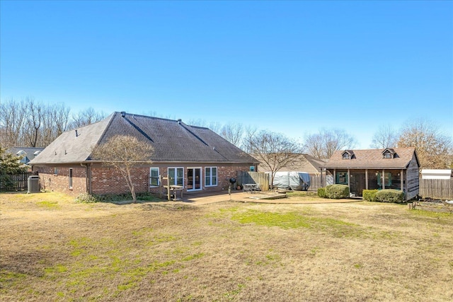 back of property with brick siding, a fenced backyard, a patio area, and a yard