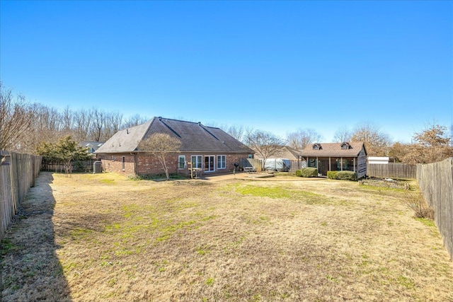 rear view of property featuring brick siding, a fenced backyard, and a yard