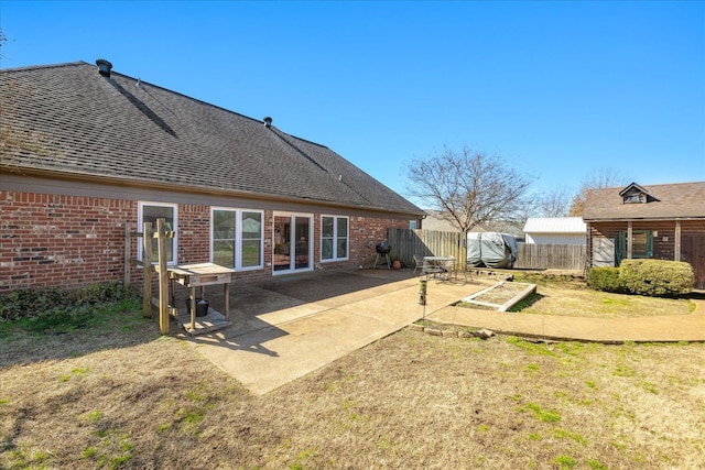 rear view of house featuring a patio area, a shingled roof, fence, and brick siding