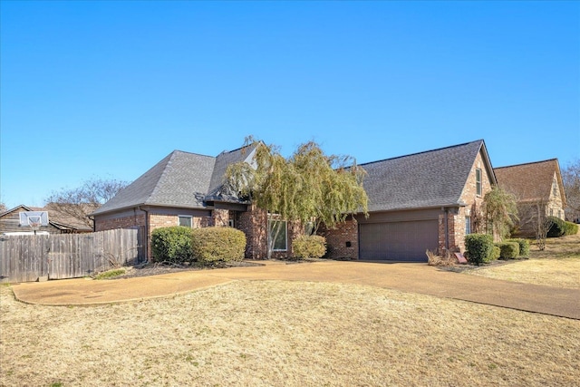 view of front of home featuring an attached garage, brick siding, a front yard, and fence