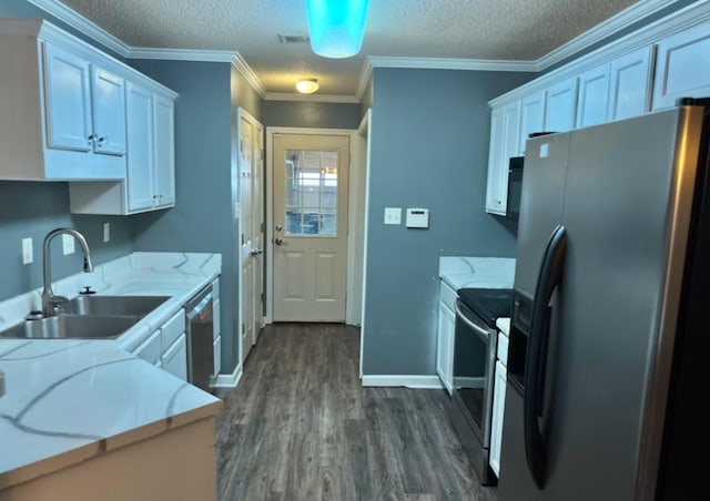 kitchen with dark wood finished floors, stainless steel appliances, ornamental molding, white cabinetry, and a sink