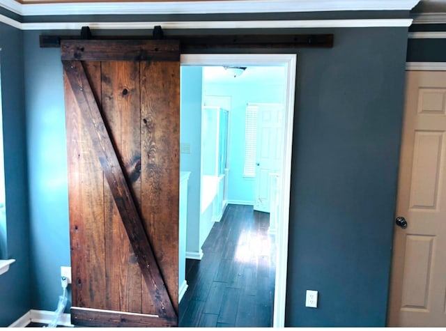 corridor with crown molding, dark wood finished floors, baseboards, and a barn door