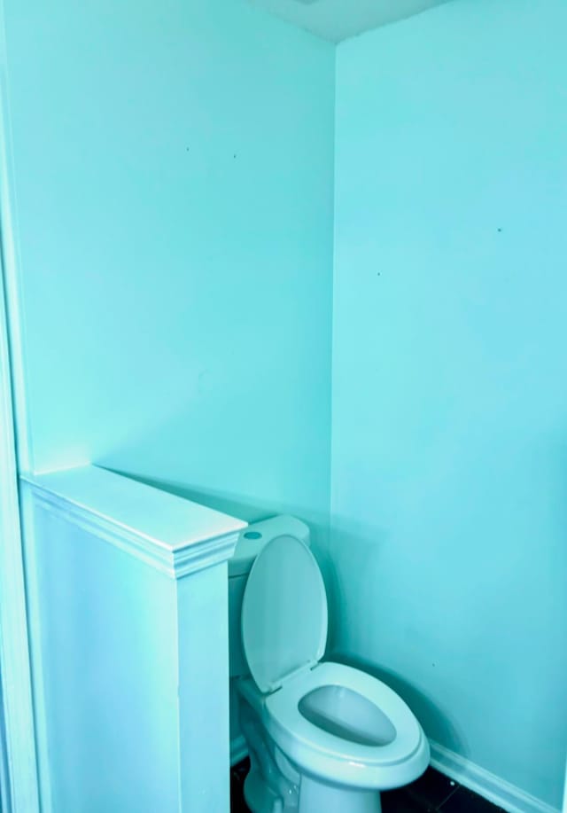 bathroom with toilet, baseboards, and tile patterned floors