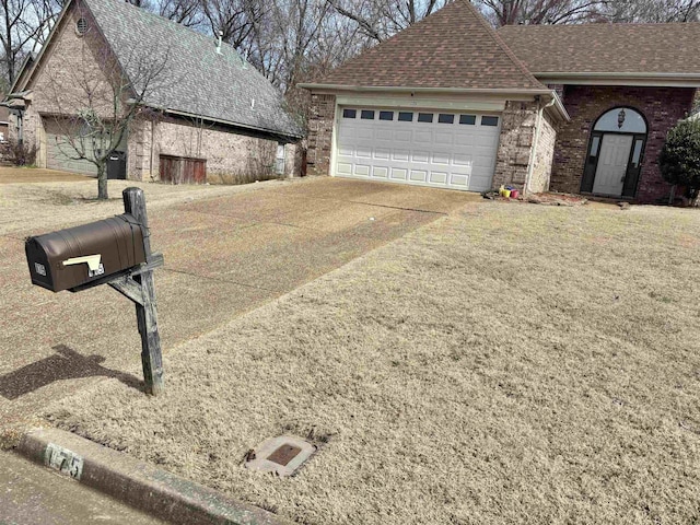 view of front of house featuring a garage, driveway, brick siding, and a shingled roof