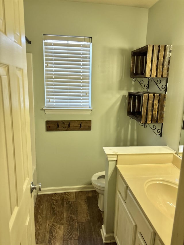 bathroom featuring baseboards, vanity, toilet, and wood finished floors