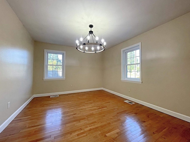 spare room with light wood-style floors, visible vents, and baseboards