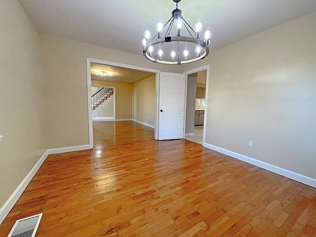 unfurnished dining area featuring baseboards, light wood-style flooring, visible vents, and an inviting chandelier