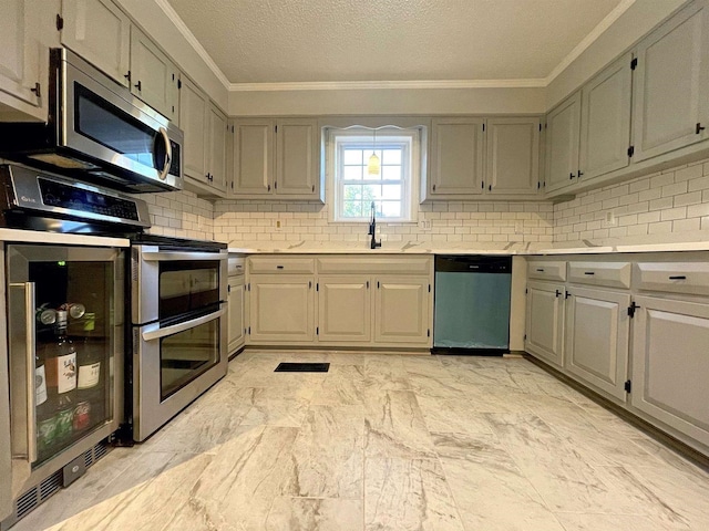 kitchen with light countertops, ornamental molding, appliances with stainless steel finishes, marble finish floor, and decorative backsplash