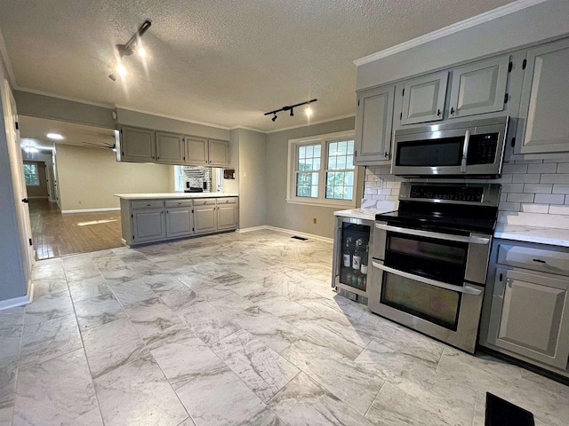 kitchen featuring wine cooler, stainless steel appliances, light countertops, gray cabinets, and crown molding