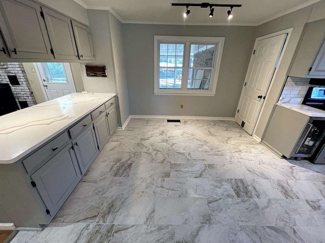 kitchen featuring ornamental molding, marble finish floor, light countertops, gray cabinetry, and a wealth of natural light