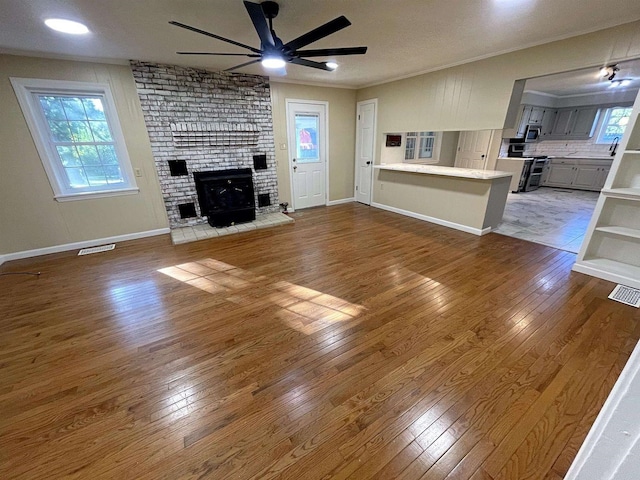 unfurnished living room with ornamental molding, visible vents, and hardwood / wood-style flooring