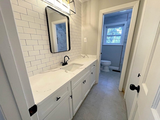 bathroom with baseboards, decorative backsplash, toilet, tile patterned floors, and vanity