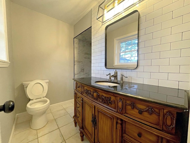 bathroom with toilet, vanity, baseboards, backsplash, and tile patterned floors