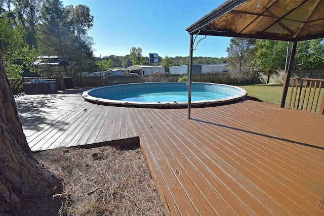 view of swimming pool featuring a yard, a fenced backyard, a wooden deck, and a fenced in pool