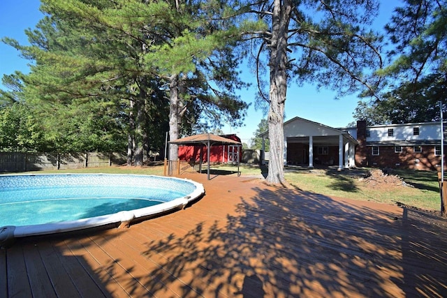 pool with fence, a wooden deck, and a gazebo