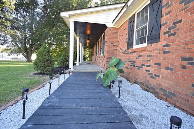 view of side of home with ceiling fan, a lawn, and brick siding