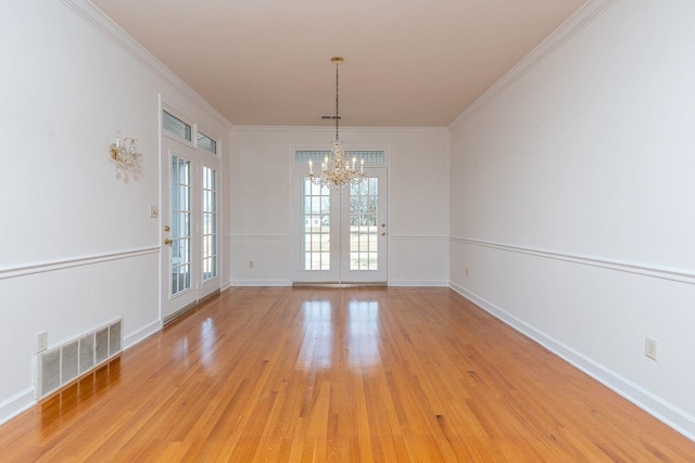 unfurnished dining area with light wood-style floors, a chandelier, visible vents, and ornamental molding