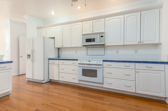 kitchen with white appliances, light wood-style floors, white cabinets, tile counters, and crown molding