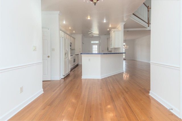 kitchen featuring a peninsula, light wood-style flooring, white refrigerator with ice dispenser, and ornamental molding