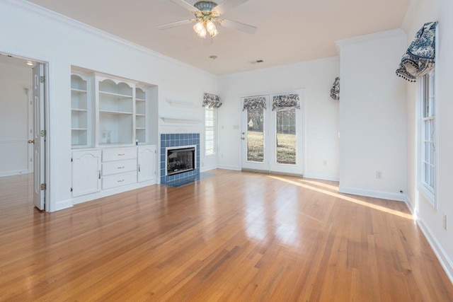 unfurnished living room featuring a fireplace, visible vents, light wood-style flooring, ornamental molding, and ceiling fan