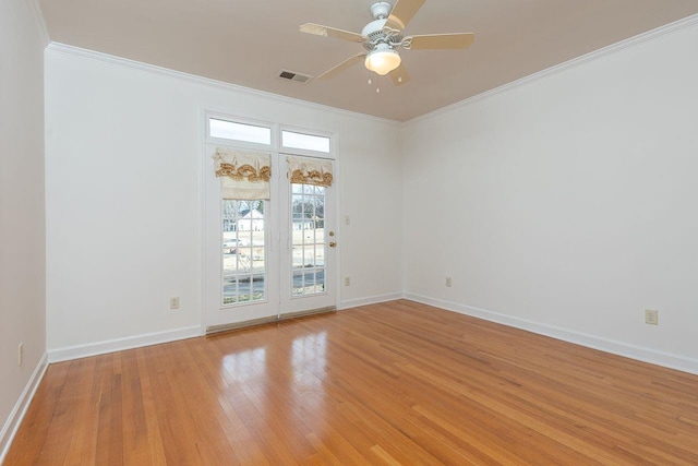 spare room featuring ceiling fan, visible vents, baseboards, light wood-type flooring, and crown molding