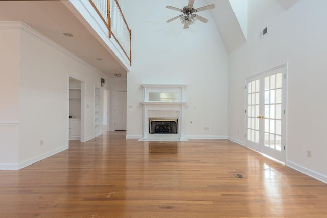 unfurnished living room with built in shelves, visible vents, a fireplace with flush hearth, light wood-type flooring, and baseboards