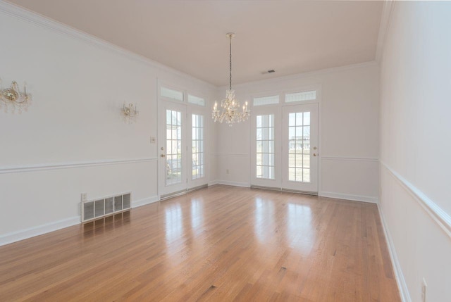 unfurnished room with ornamental molding, light wood finished floors, a chandelier, and visible vents