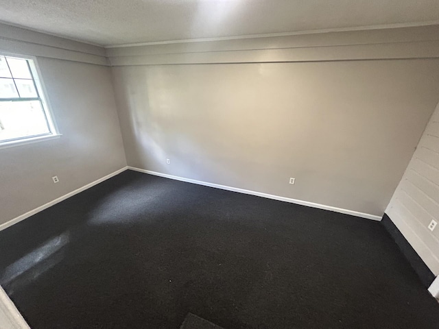 unfurnished room featuring a textured ceiling and baseboards