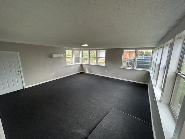 empty room featuring baseboards, a textured ceiling, and a wall mounted air conditioner