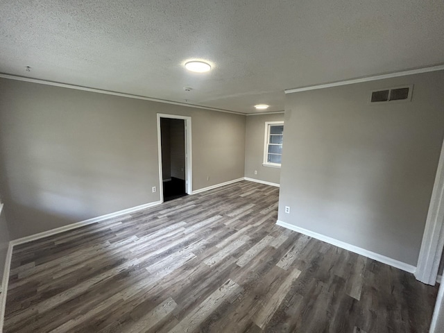 spare room with dark wood-style floors, visible vents, and crown molding