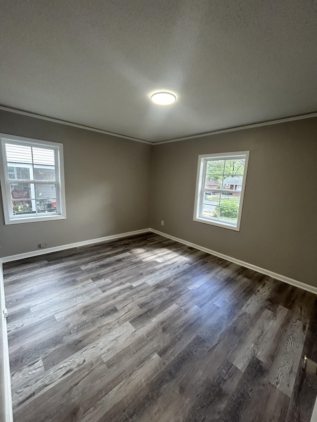 unfurnished room featuring ornamental molding, dark wood-style flooring, a textured ceiling, and baseboards