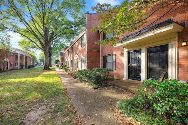 view of home's exterior with brick siding and a lawn