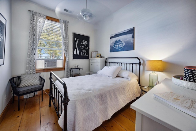 bedroom featuring baseboards, cooling unit, visible vents, and hardwood / wood-style floors