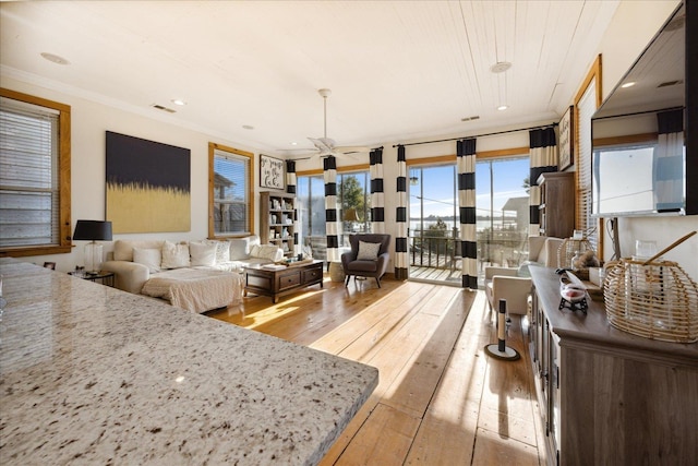 interior space with light wood finished floors, ceiling fan, visible vents, and crown molding