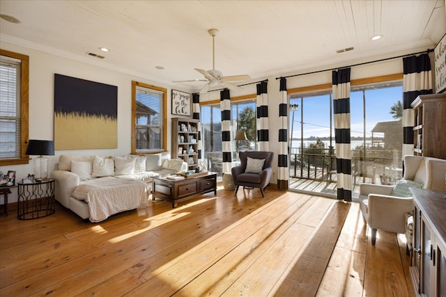 living area featuring a healthy amount of sunlight, crown molding, and hardwood / wood-style flooring