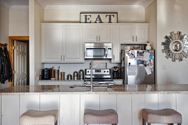 kitchen featuring appliances with stainless steel finishes, ornamental molding, decorative backsplash, and a sink