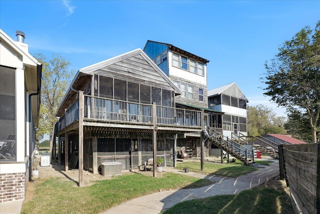 rear view of house featuring a sunroom and stairs