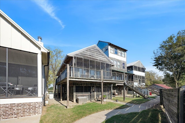 back of property featuring a sunroom, fence, stairway, and a yard