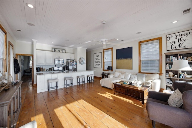 living room featuring recessed lighting, visible vents, crown molding, and hardwood / wood-style floors