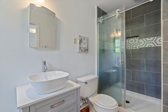 bathroom with toilet, a shower stall, and vanity