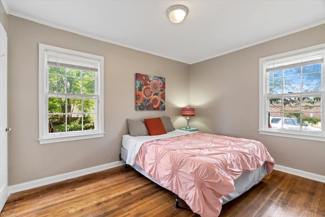 bedroom with ornamental molding, baseboards, and wood finished floors