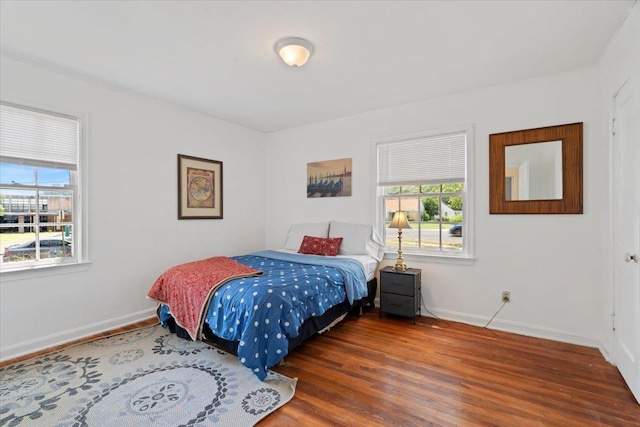 bedroom with multiple windows, baseboards, and wood finished floors