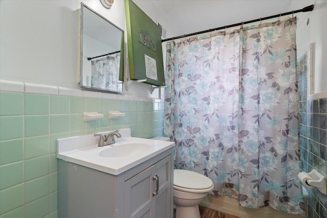 full bathroom with toilet, a wainscoted wall, a shower with shower curtain, vanity, and tile walls