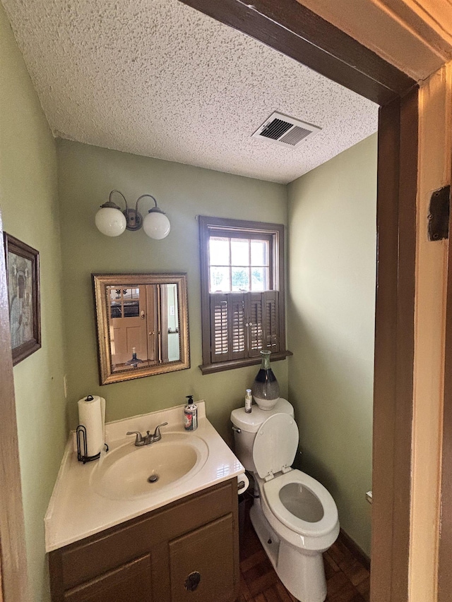 bathroom with toilet, visible vents, a textured ceiling, and vanity