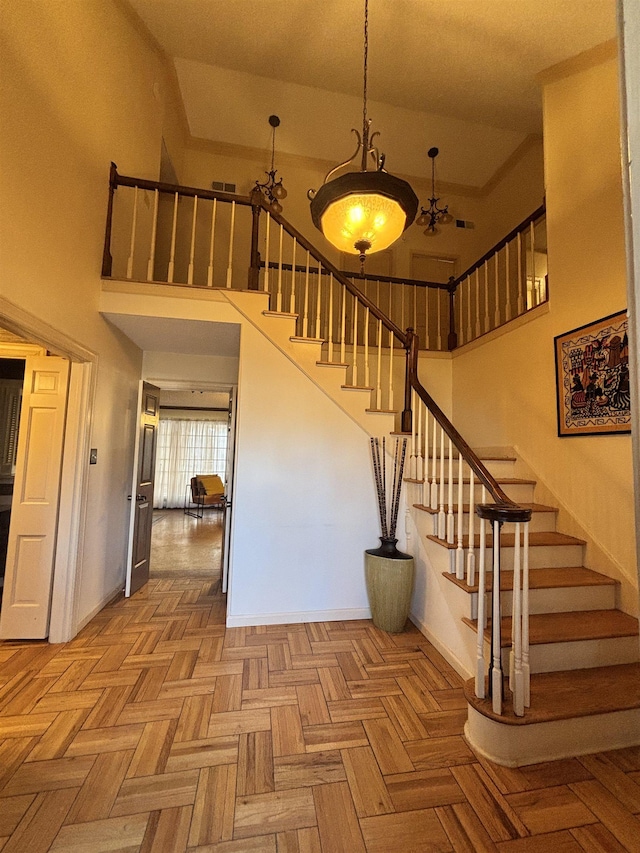 stairway featuring a high ceiling, visible vents, and baseboards