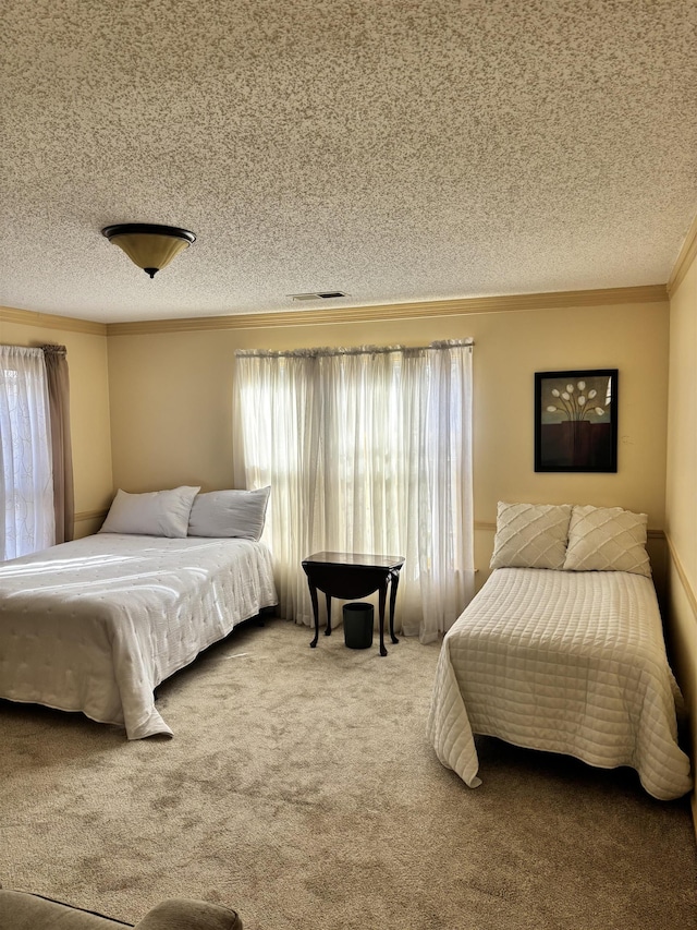 bedroom with ornamental molding, visible vents, carpet flooring, and a textured ceiling