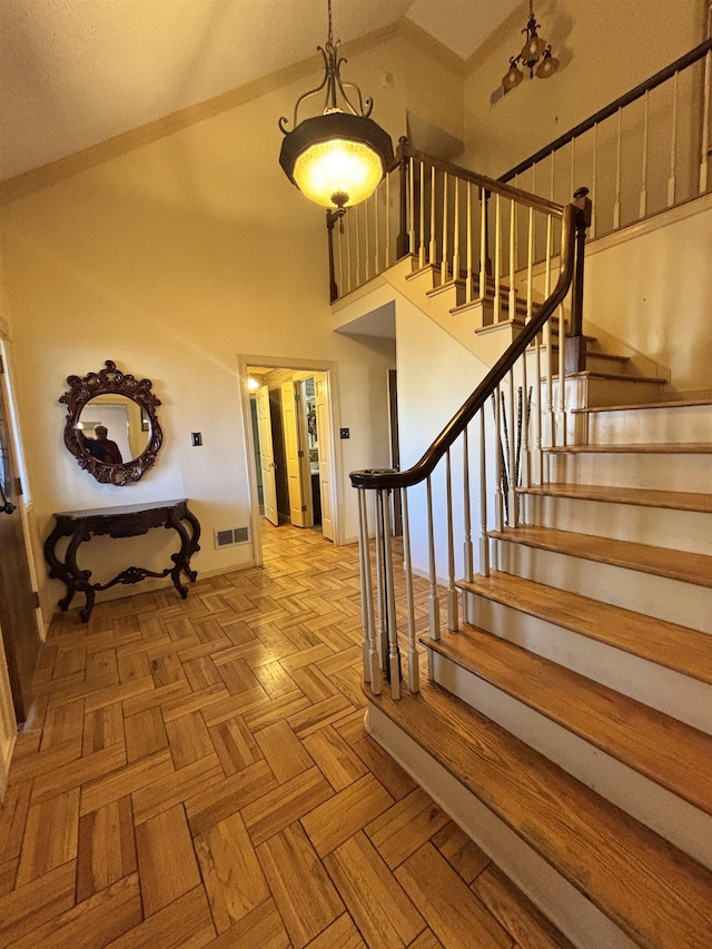 staircase with high vaulted ceiling and visible vents