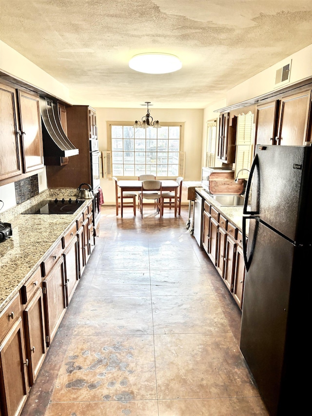 kitchen featuring light stone countertops, black appliances, visible vents, and a textured ceiling